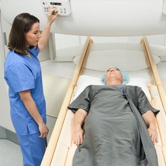 Middle aged woman with illness and technician during MRI in hospital laboratory. People and disease prevention with magnetic resonance imaging