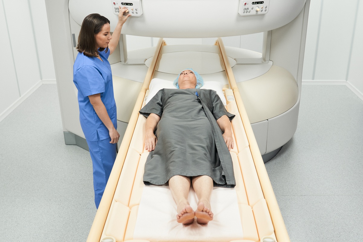 Middle aged woman with illness and technician during MRI in hospital laboratory. People and disease prevention with magnetic resonance imaging